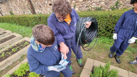 insegnante con tubo dell'irrigazione che da indicazioni al ragazzo