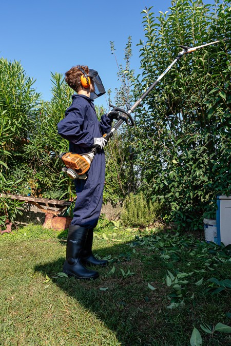 Ragazzo con taglia siepi che taglia la siepe