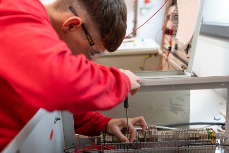 Ragazzo che con il cacciavite fissa il cavo dell'impianto all'interno del quadro elettrico